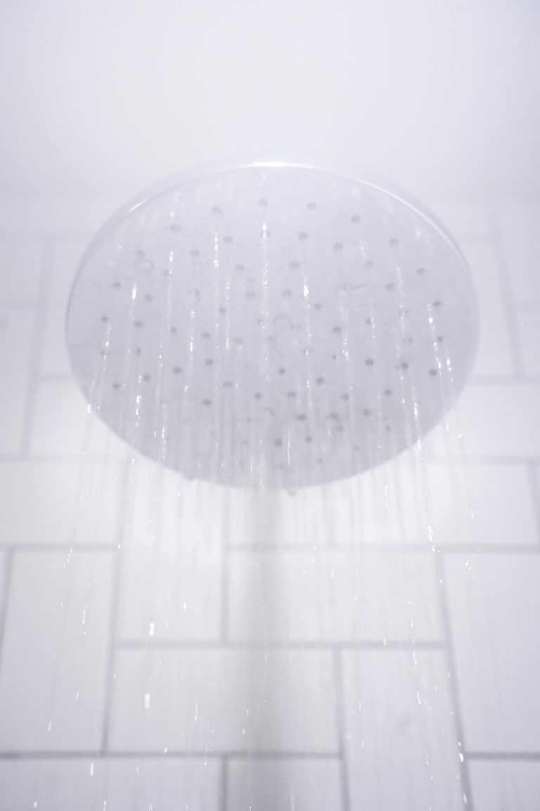 water from round gray stainless steel shower head